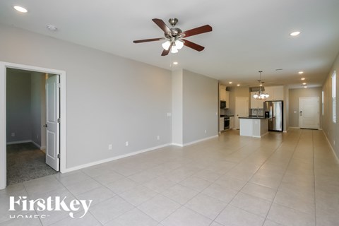 A spacious room with a ceiling fan and a kitchen in the background.