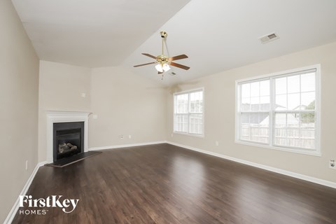 an empty living room with a ceiling fan and a fireplace