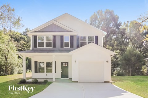 the exterior of a white house with a driveway in front of it