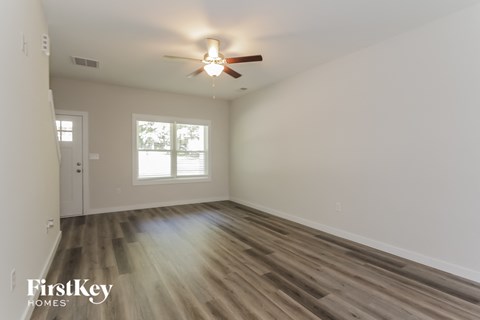 an empty living room with a ceiling fan and a window