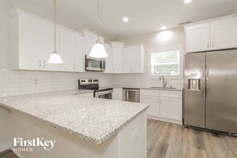 a kitchen with white cabinets and a marble counter top