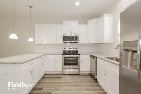 a white kitchen with white cabinets and stainless steel appliances