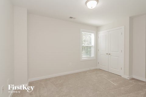 a bedroom with white walls and a white door and a window