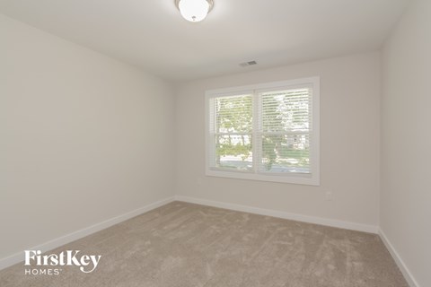 the bedroom of a house with a window and white walls