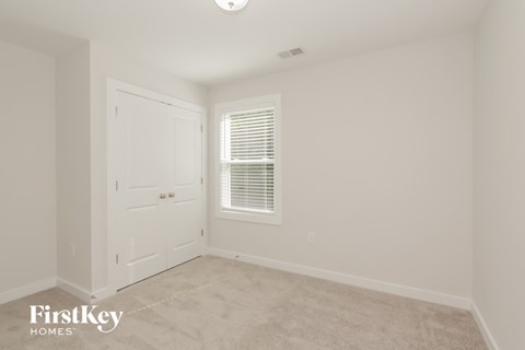 a bedroom with white walls and a door and a window