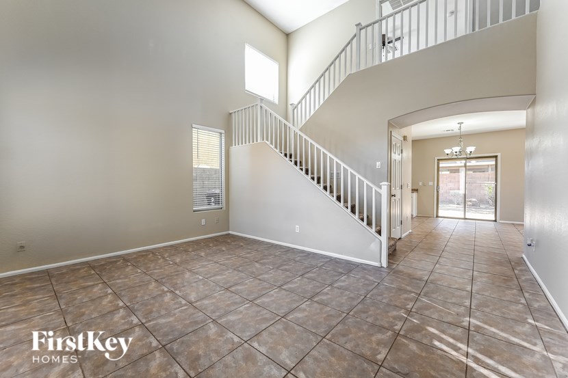 A spacious empty room with a staircase and a door leading to another room.