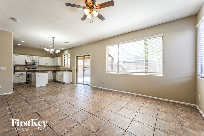 A spacious living room with a ceiling fan and tiled flooring.