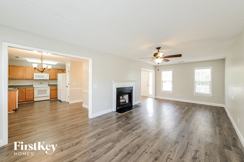 an empty living room with a fireplace and a kitchen