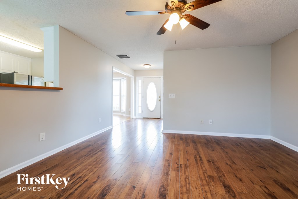 A spacious room with wooden floors and a ceiling fan.