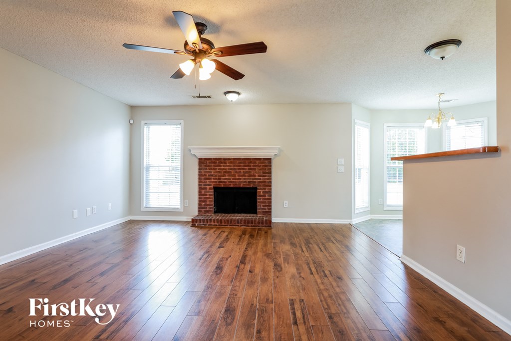 A spacious living room with a fireplace and wood flooring.