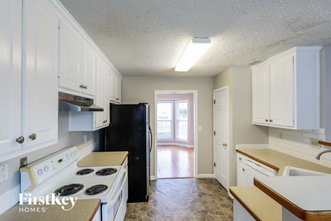 A kitchen with white cabinets and a black refrigerator.