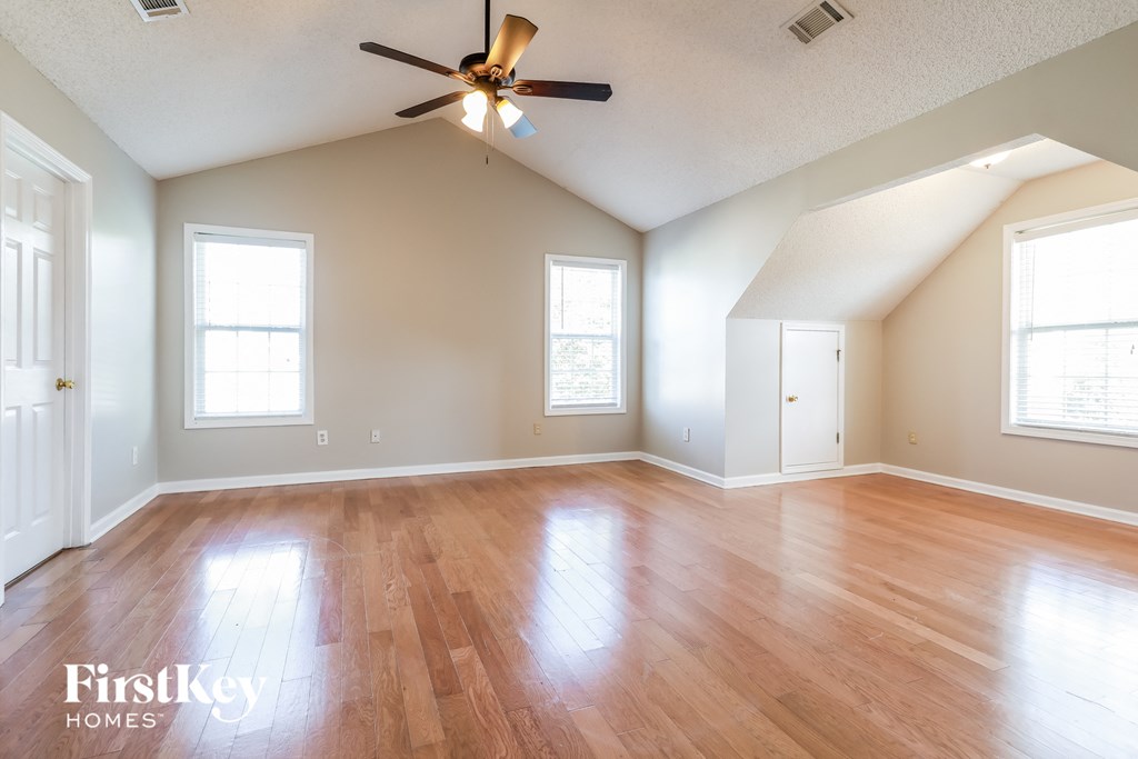 A spacious room with wooden floors and a ceiling fan.