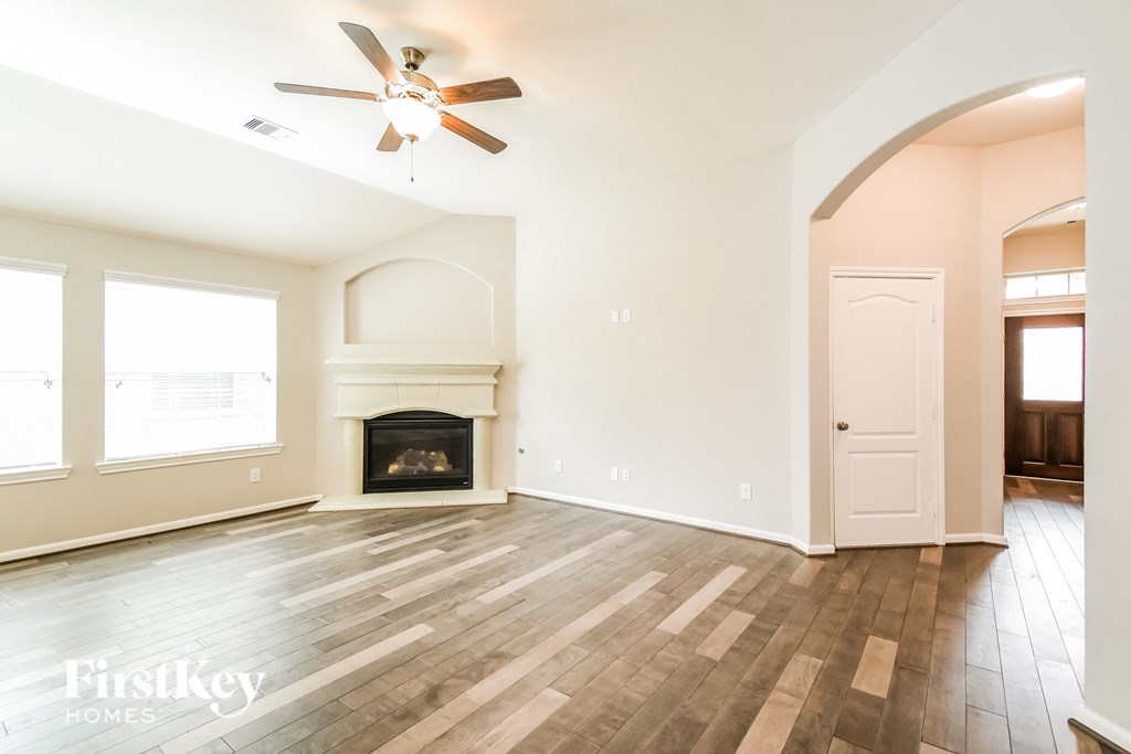 an empty living room with a fireplace and a ceiling fan