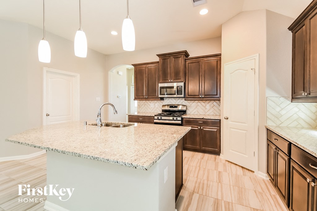 a kitchen with brown cabinets and a marble counter top