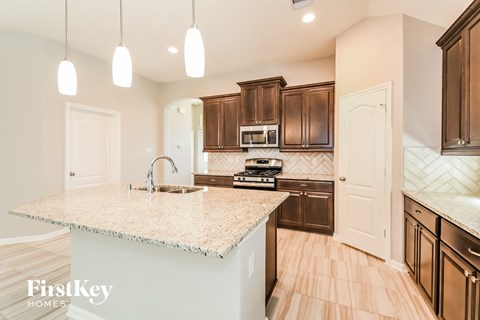 a kitchen with brown cabinets and a marble counter top