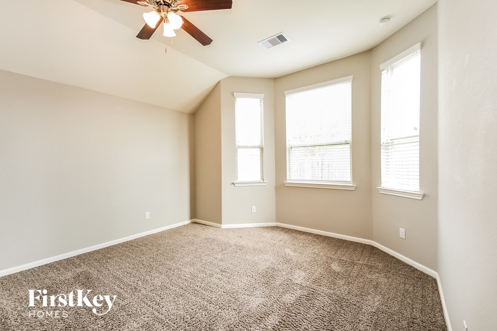 a spacious living room with three windows and a ceiling fan