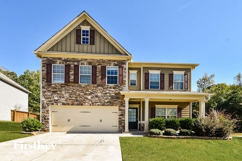 a stone house with a garage door and a lawn