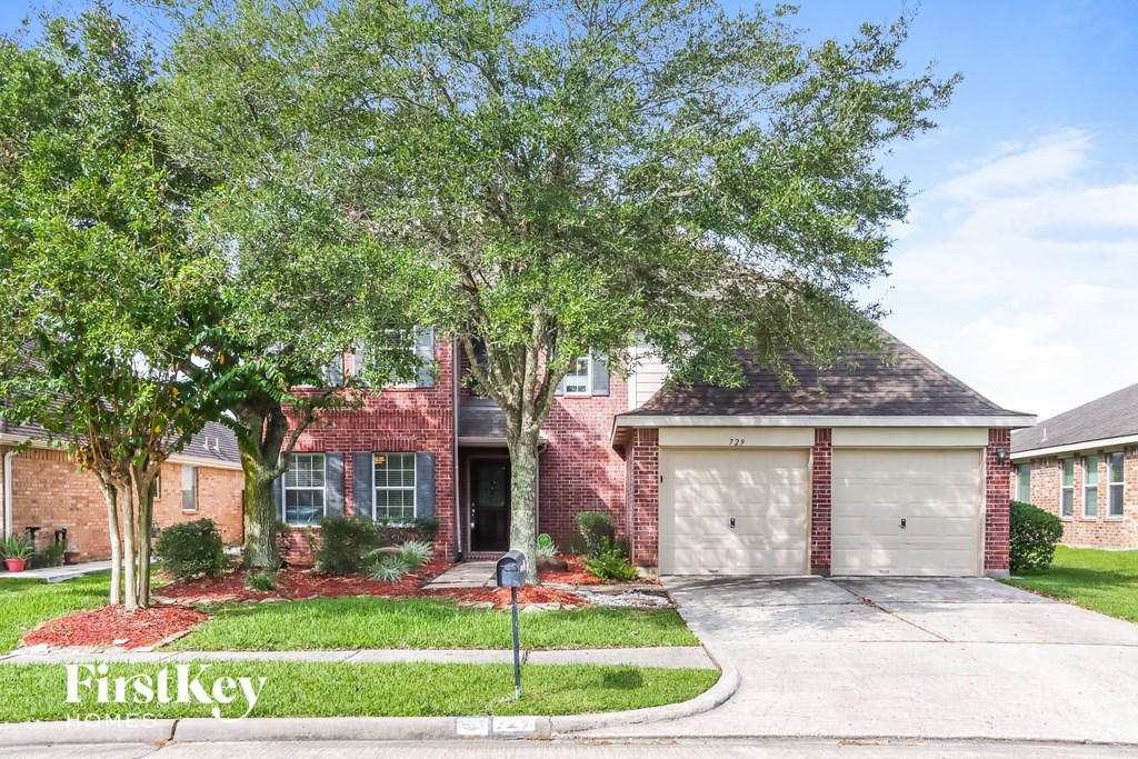 A house with a garage and a tree in front of it.