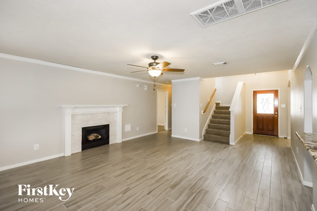 A spacious living room with a fireplace and a staircase leading to another room.