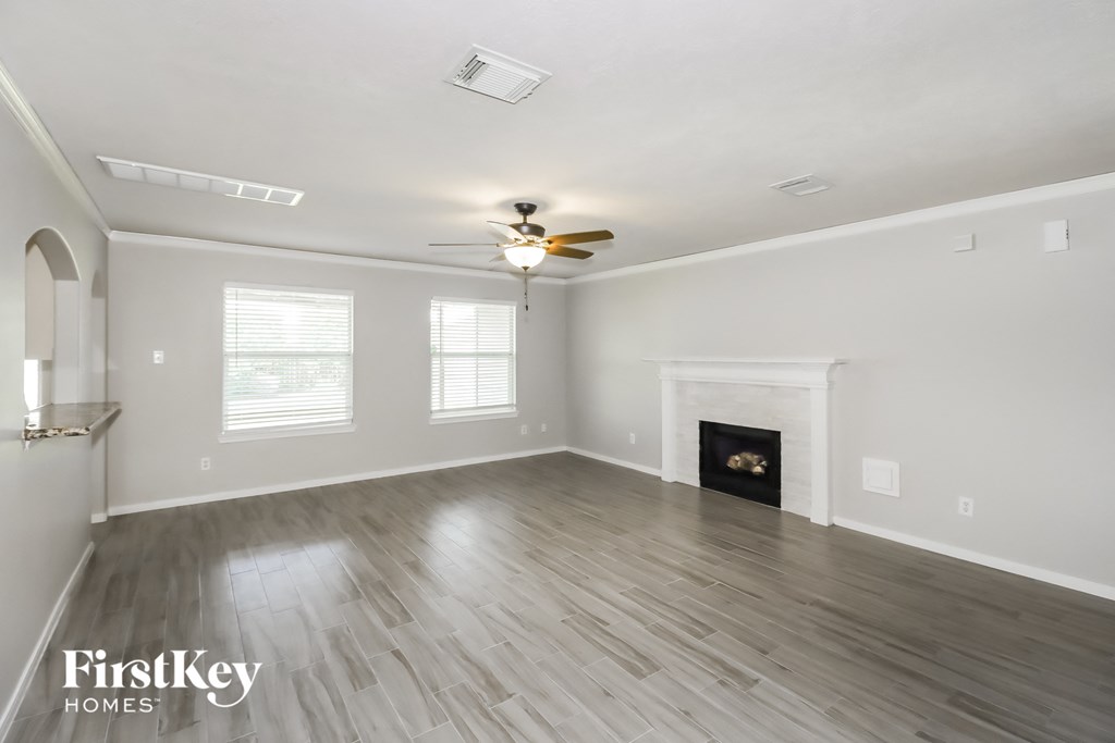 A spacious living room with a fireplace and a ceiling fan.