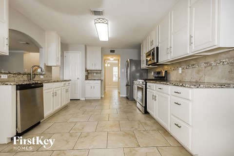A kitchen with white cabinets and appliances.
