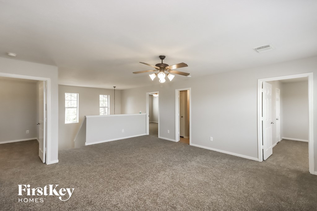 A spacious room with a ceiling fan and carpeted floor.