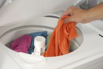 person putting clothes into a washing machine