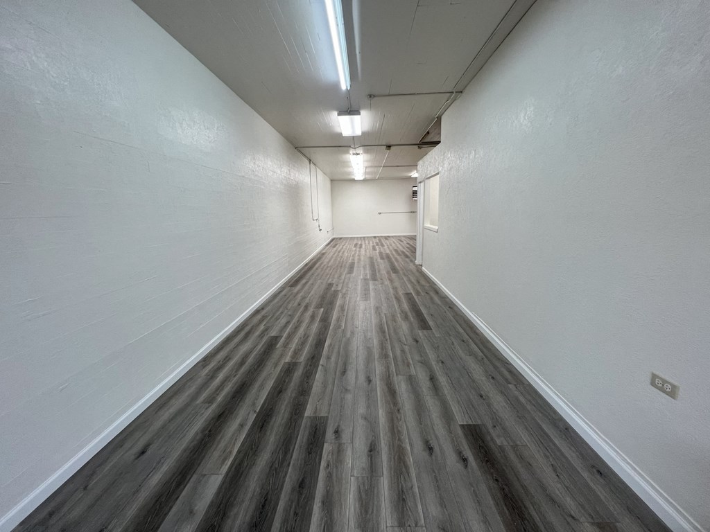 a long hallway with white walls and wood floors