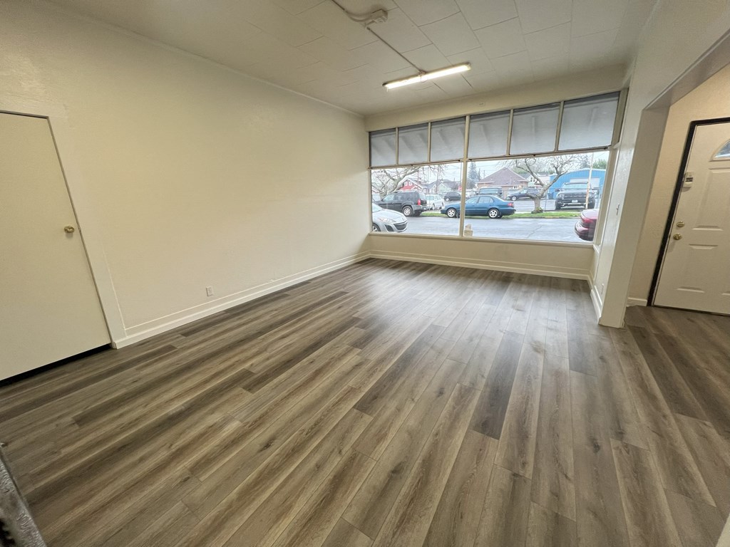 an empty living room with wood flooring and a window