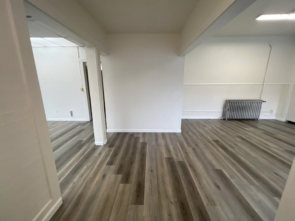 an empty living room with wooden floors and white walls