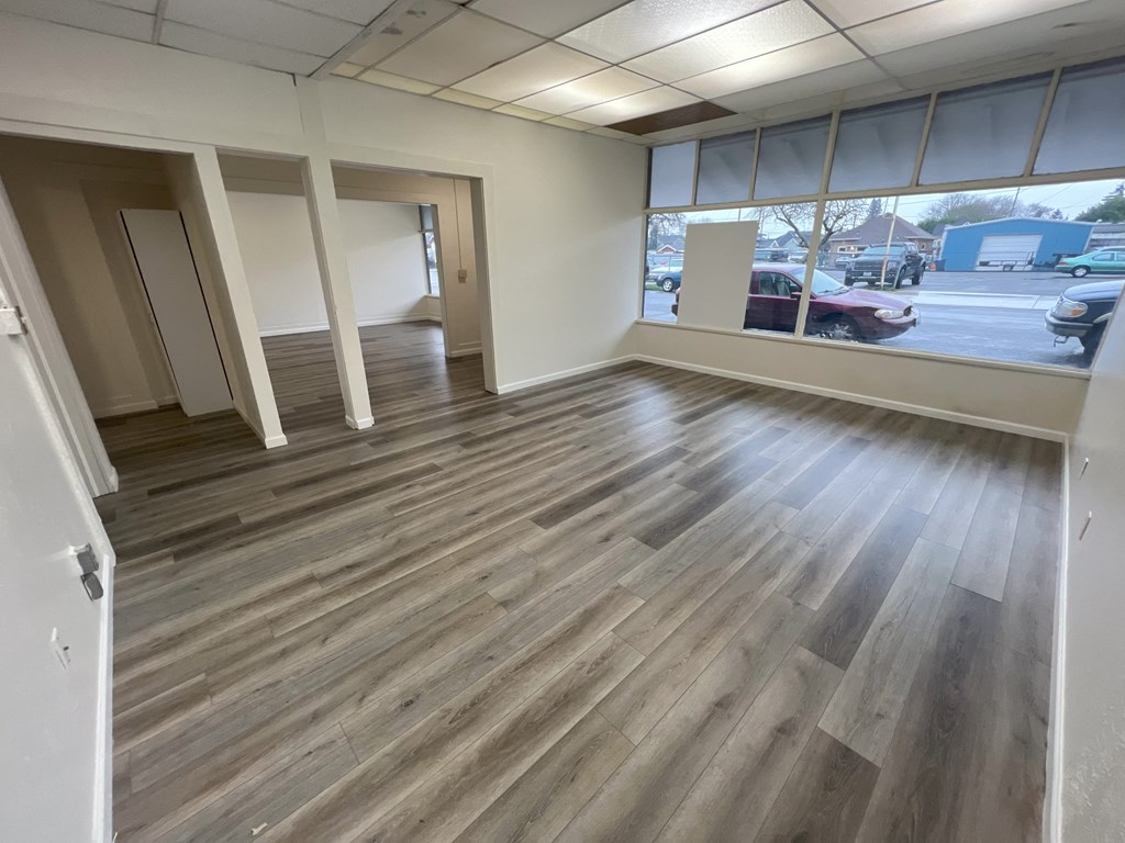 an empty living room with wood floors and a window