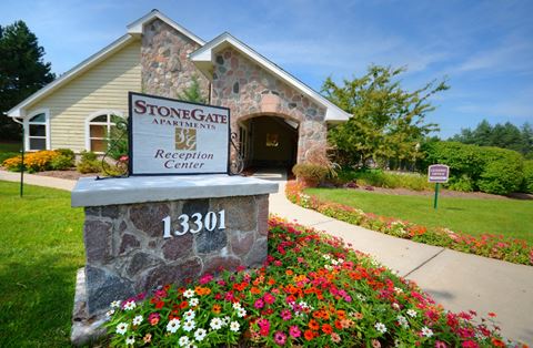 the stonegate apartments and recreation center entrance to the building with flowers