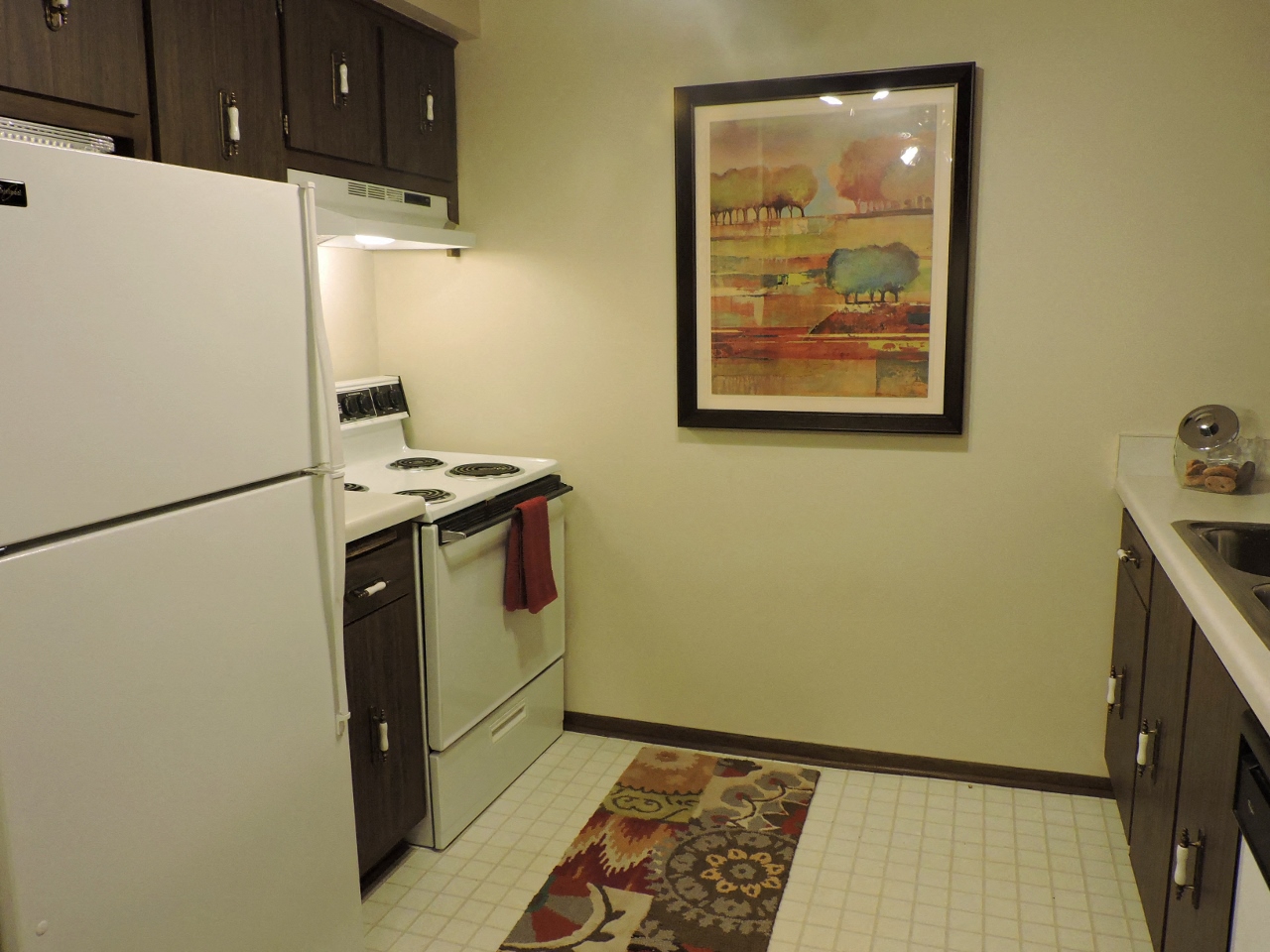 a kitchen with white appliances and a painting on the wall