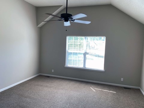 a bedroom with a ceiling fan and a window