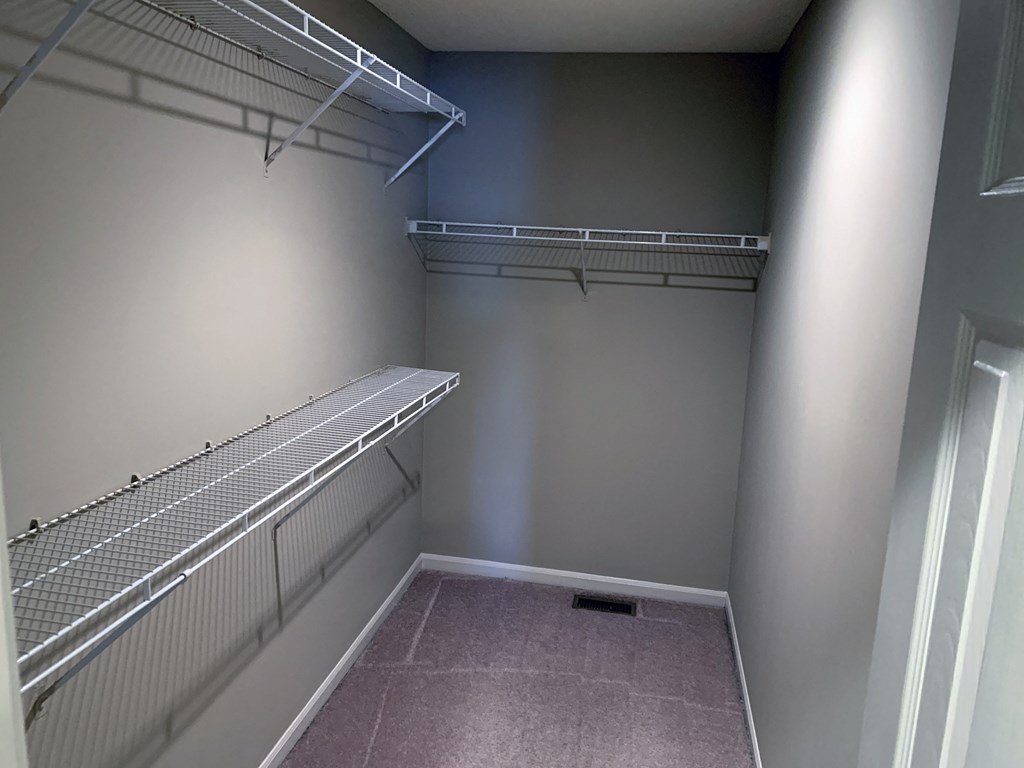 a walk in closet with a shelf and a window
