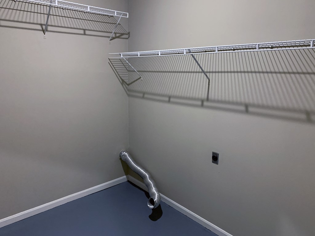a walk in closet with a wire shelf on the wall