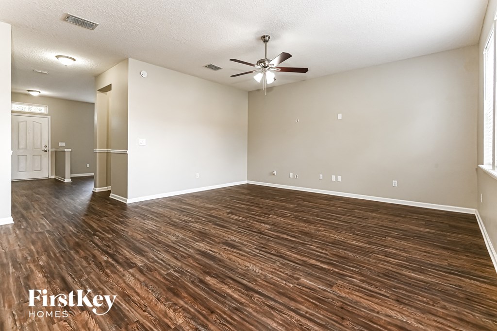 an empty living room with wood flooring and a ceiling fan