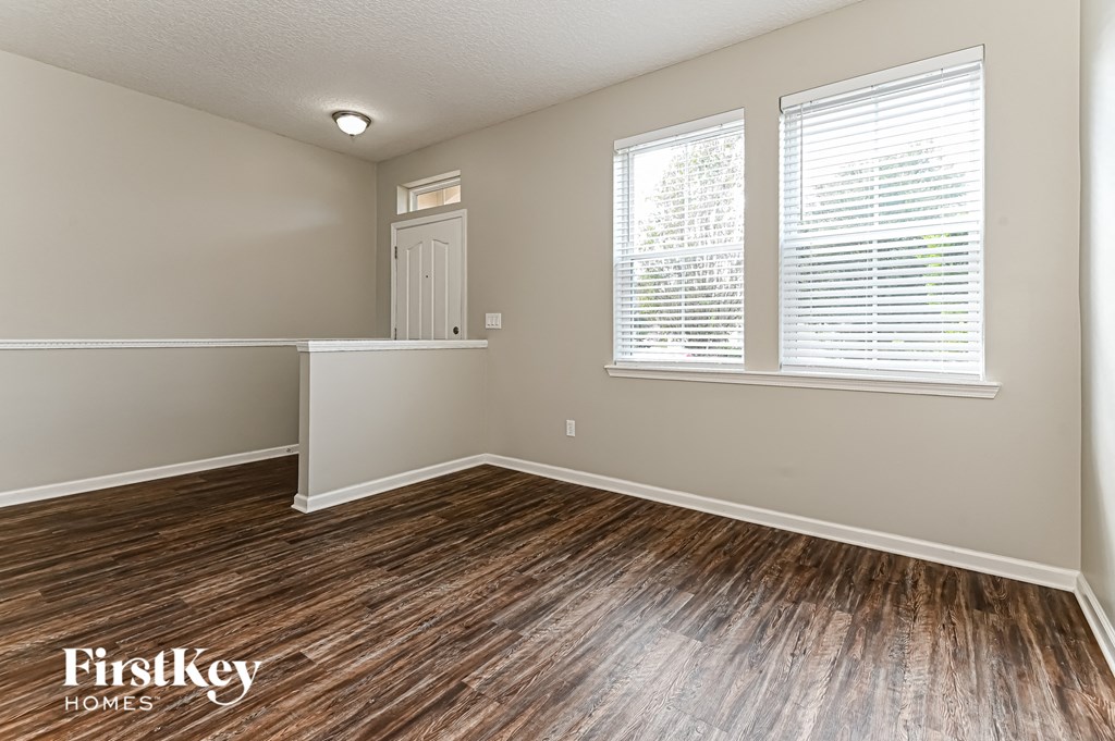 the living room of a house with wood flooring and two windows