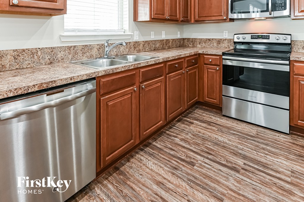 a kitchen with wood flooring and stainless steel appliances