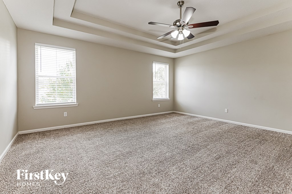 an empty living room with a ceiling fan and window