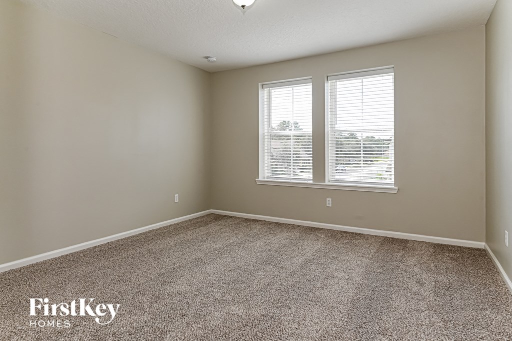 a bedroom with two windows and a carpeted floor