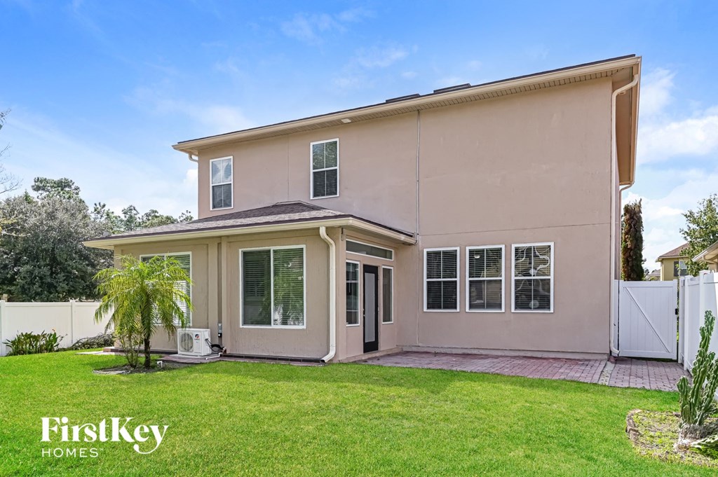 a beige house with a lawn and a white fence