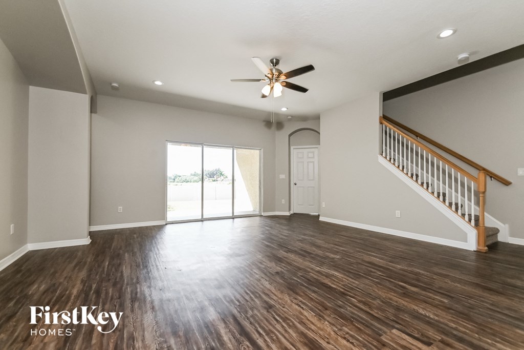 A spacious room with wood flooring and a ceiling fan.