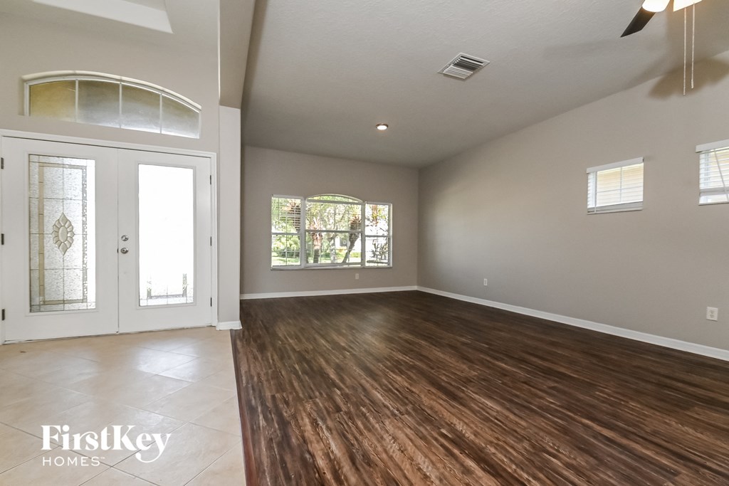 A spacious room with wooden floors and a large window.