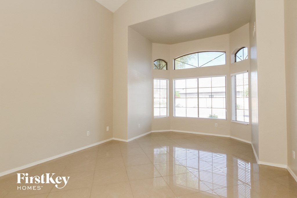 an empty living room with large windows and tiled floors