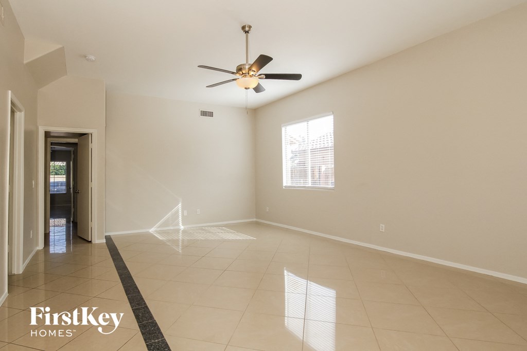 an empty living room with a ceiling fan and tiled floor