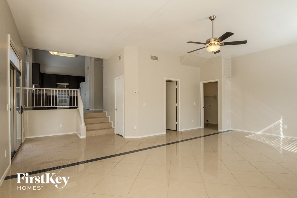 an empty living room with a ceiling fan and tiled floor