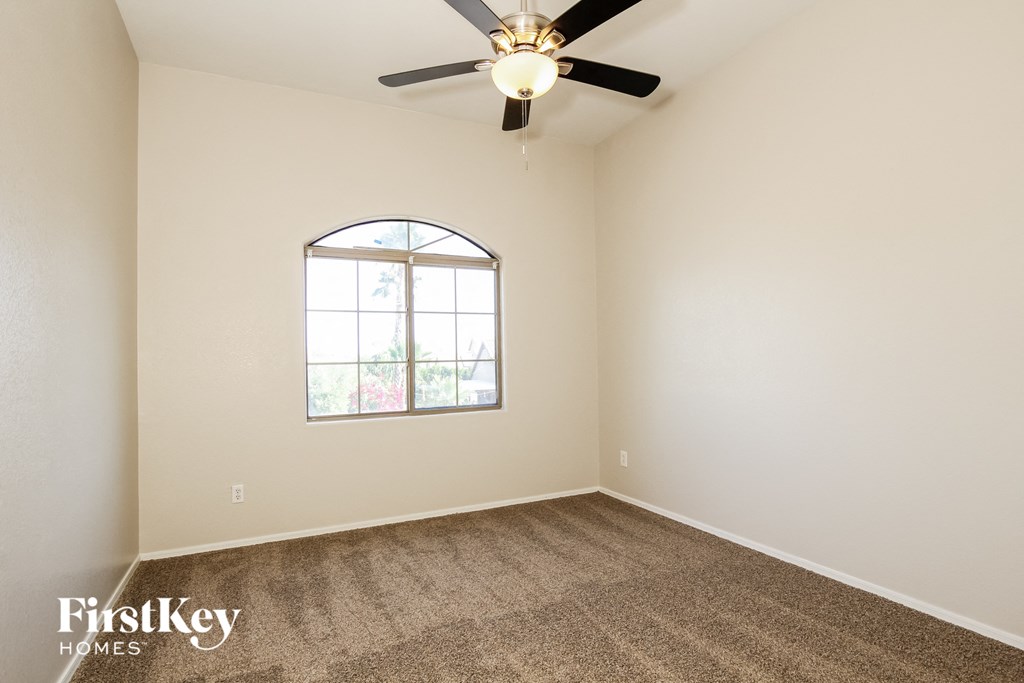 the spacious living room with carpeting and a ceiling fan