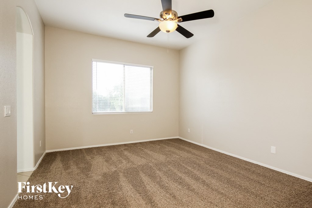 the spacious living room with carpeting and a ceiling fan