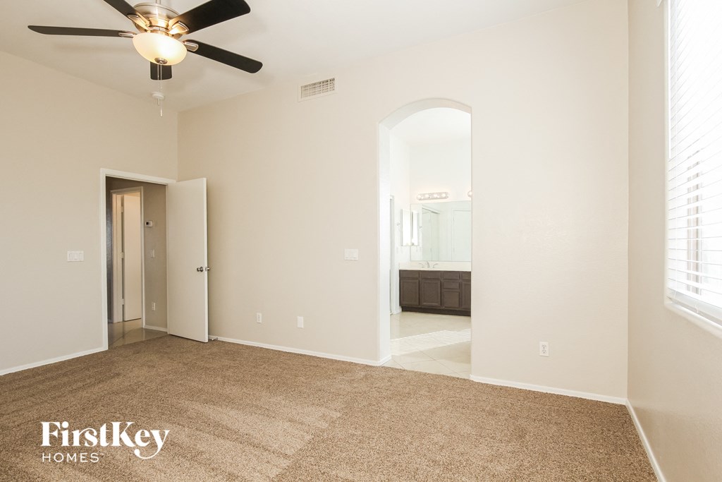 a spacious living room with carpet and a ceiling fan